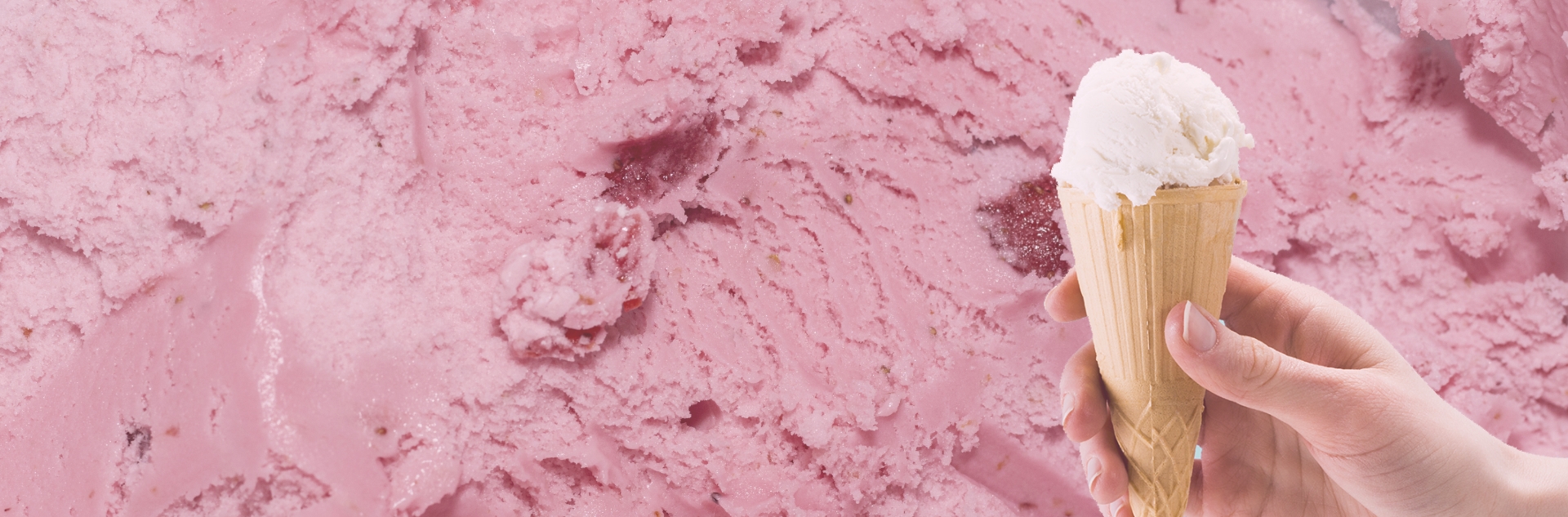 Mano sosteniendo un cucurucho de helado artesanal sobre un fondo rosa
